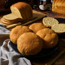 low carb sliced bread on a wooden board next to 5 rolls of low card bread rolls