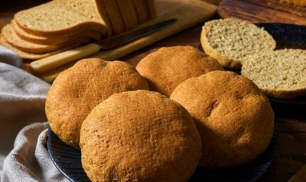 low carb sliced bread on a wooden board next to 5 rolls of low card bread rolls