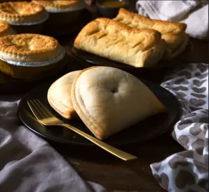 two plain meat pasties next too sausage rolls and meat pies