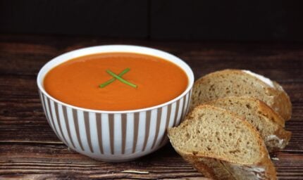 fresh tomato soup in a bowl next to freshly baked bread