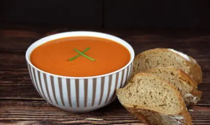 fresh tomato soup in a bowl next to freshly baked bread