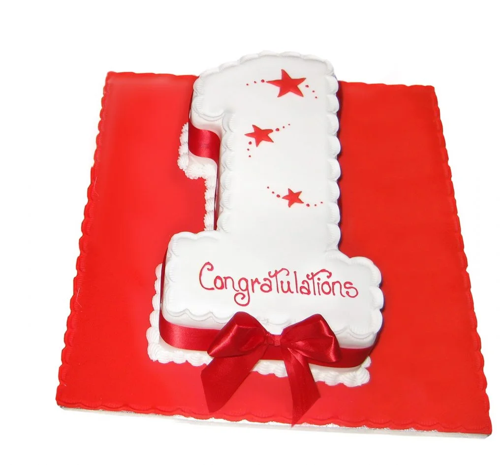 single number celebration cake topped with red stars and bow