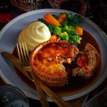 large meat pie with mash, vegetables and gravy