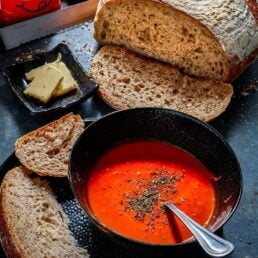 bowl of greenhalghs tomato soup next to a bread loaf