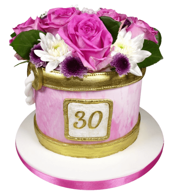 pink flower celebration cake with flowers on top of the cake and gold ribbons wrapped around the cake