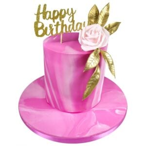 pretty pink celebration cake with a pink flower and gold leaves topped with a happy birthday topper